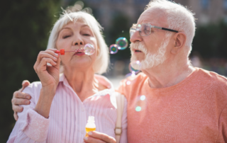 Elderly couple having fun anf blowing bubbles.