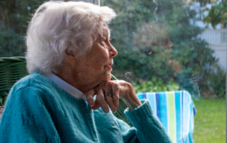HMC HomeCare Helping Seniors to Combat Loneliness. A woman is sitting alone stairing outside.