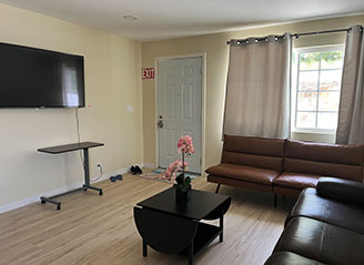 Bright living room at HMC Care Home in Honolulu with modern seating, flat-screen TV, and natural light, creating a cozy and welcoming space for residents.