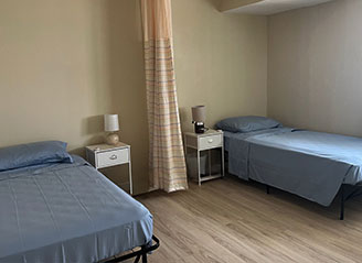 Semi-private bedroom at HMC Care Home with two hospital beds, privacy curtain, and clean design to ensure comfort and dignity for every resident.