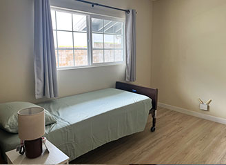 Private bedroom at HMC Care Home featuring a hospital bed, natural lighting, and minimalist design for peaceful, personalized residential care.