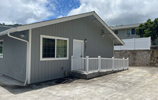 Exterior of HMC Care Home in Honolulu featuring gray siding, ramp access, and a secure, private setting designed for personalized senior residential care.