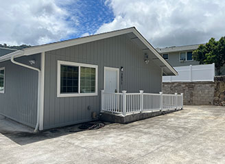 Exterior of HMC Care Home in Honolulu featuring gray siding, ramp access, and a secure, private setting designed for personalized senior residential care.