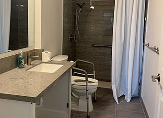 Accessible bathroom at HMC Care Home with safety grab bars, walk-in shower, and support rails designed for comfort, independence, and senior safety.