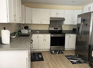 Modern kitchen at HMC Care Home in Honolulu, featuring stainless steel appliances, white cabinetry, and a clean, comfortable setting for residential care.