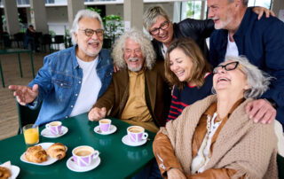 HMC Home Care seniors and family sharing laughter over coffee, symbolizing ʻohana, companionship, and the bond strengthened through in-home care support