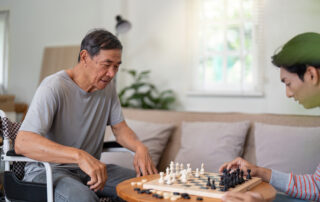 Senior receiving in-home care while playing chess with a caregiver, illustrating compassionate long-distance home care and meaningful family involvement from anywhere